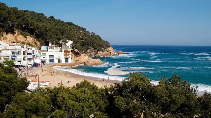 Une plage de sable bordée de bâtiments blancs et de végétation luxuriante.