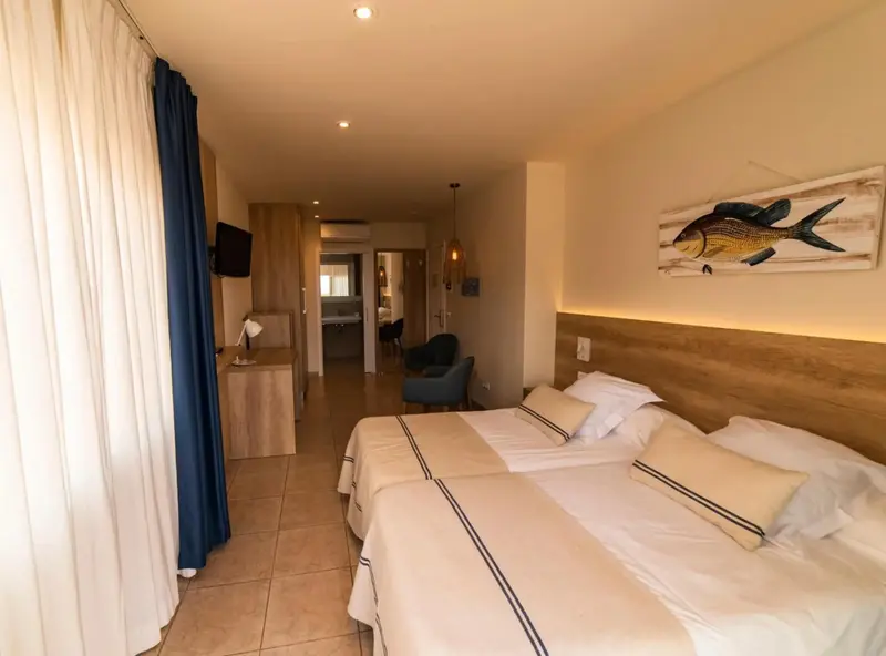 Une chambre lumineuse avec deux lits simples et un décor mural représentant un poisson.