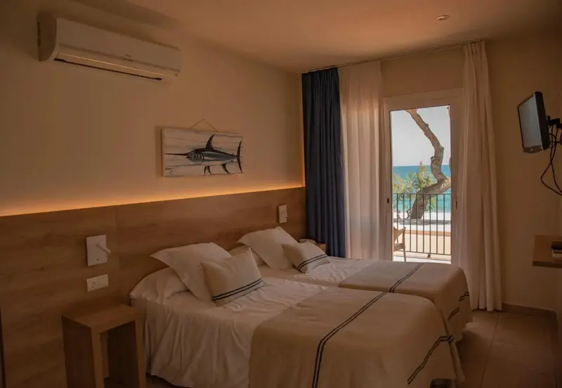 Une chambre lumineuse avec deux lits simples et vue sur la mer.