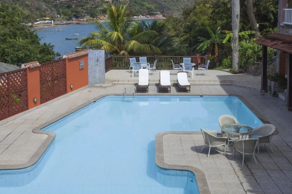 Une piscine rectangulaire avec un espace de détente et une vue sur la mer.