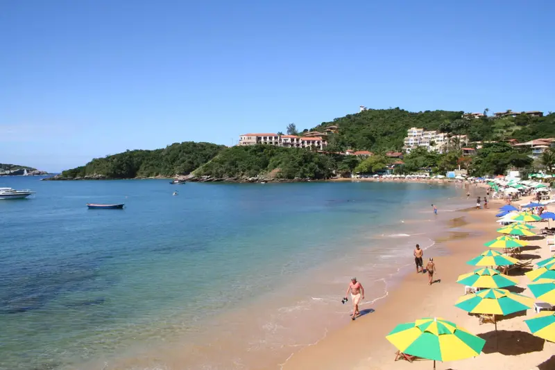 Une plage de sable fin bordée d'une eau turquoise et de parasols colorés.