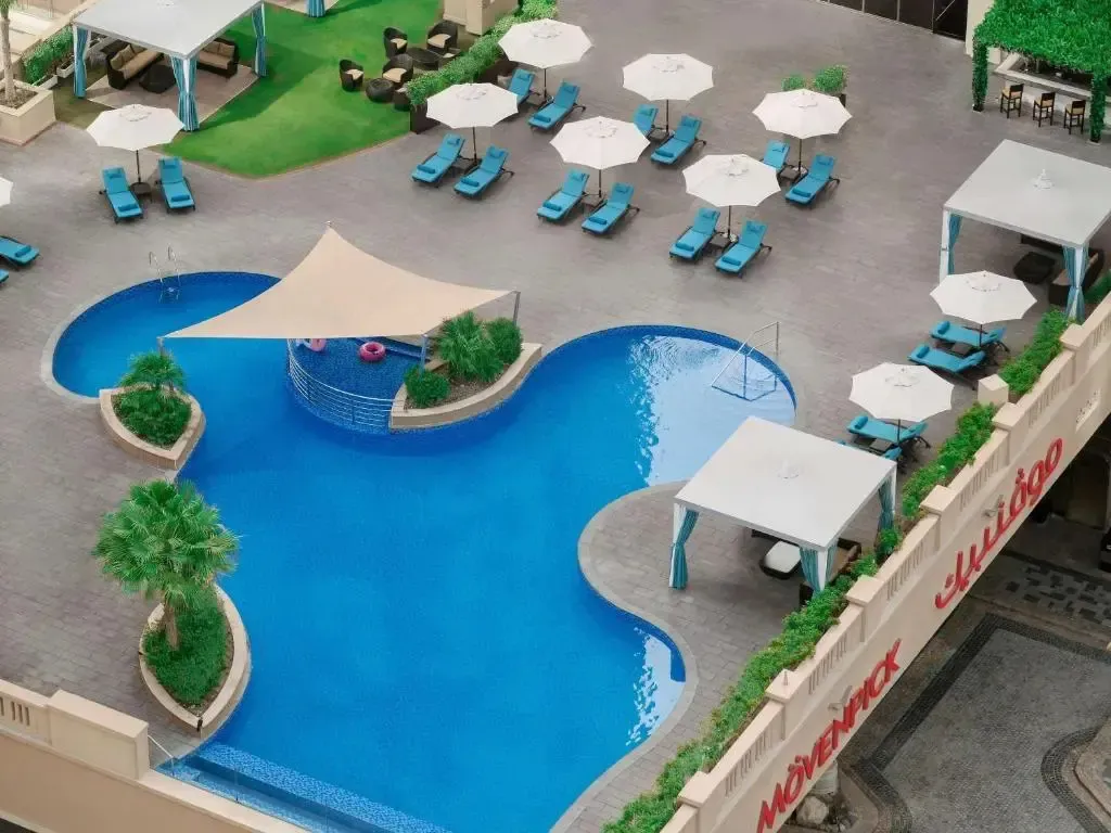 Piscine sinueuse avec transats et parasols sur une terrasse ensoleillée.