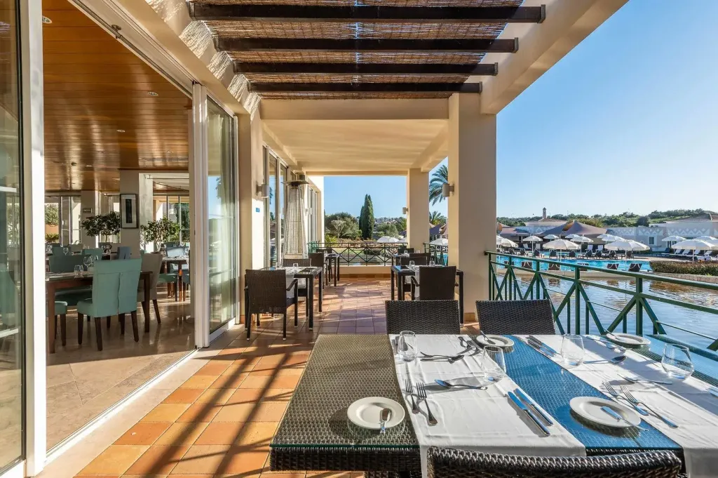 Une terrasse ombragée avec des tables dressées pour un repas.