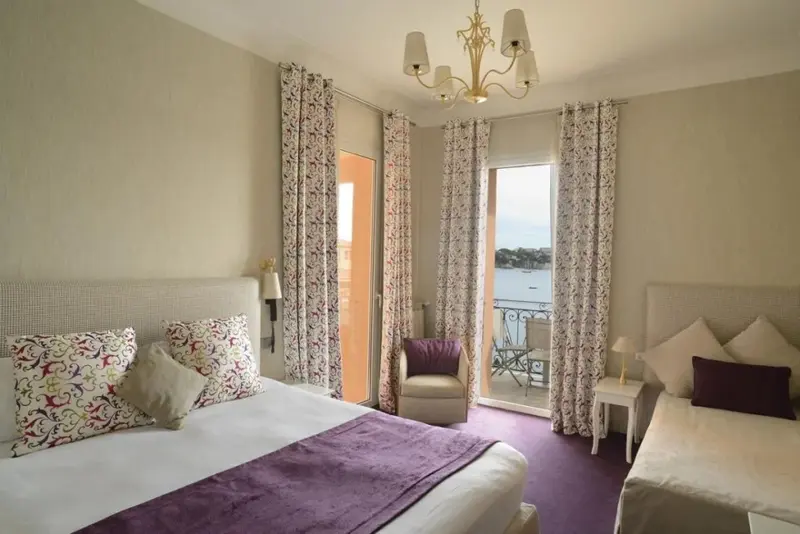 Une chambre lumineuse s'ouvre sur un balcon avec vue sur la mer.