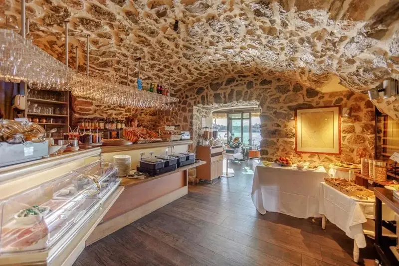 Un comptoir de buffet garni de viennoiseries et de boissons dans une salle voûtée.