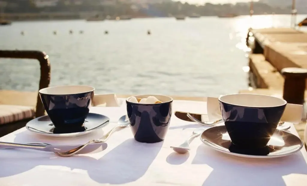 Tasses et couverts disposés sur une table en bord de mer.