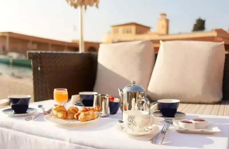 Une table est dressée avec un petit-déjeuner sur une terrasse ensoleillée.