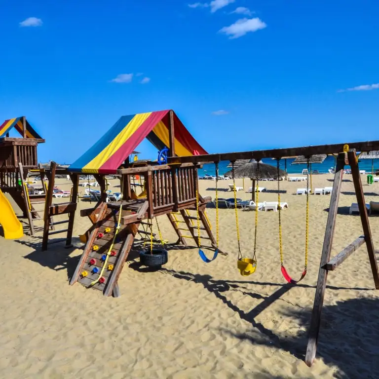 Structure de jeux en bois coloré sur une plage de sable fin.