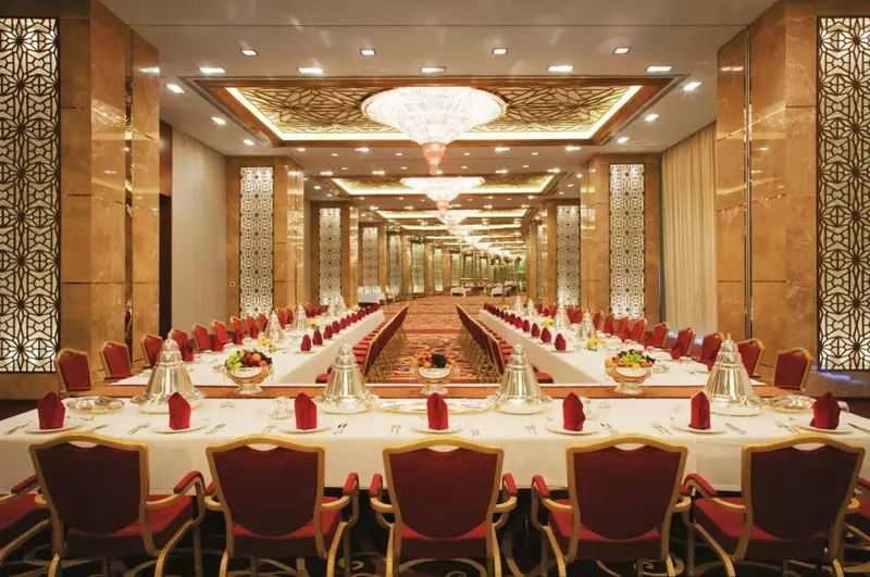 Une longue table de banquet est dressée dans une salle lumineuse et décorée.