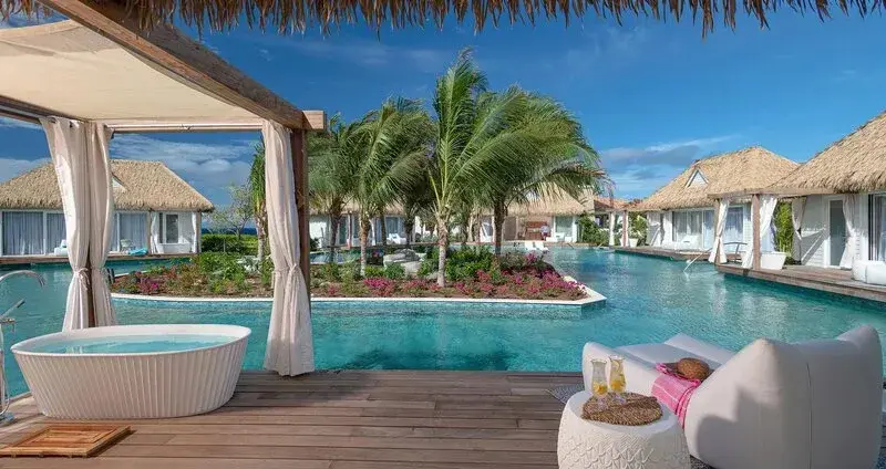 Terrasse avec baignoire et mobilier de détente face à une piscine.