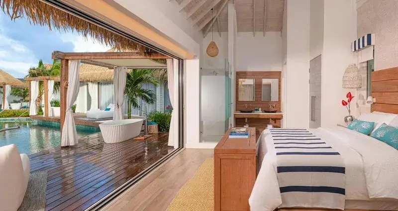 Une chambre lumineuse s'ouvre sur une terrasse avec baignoire et piscine.
