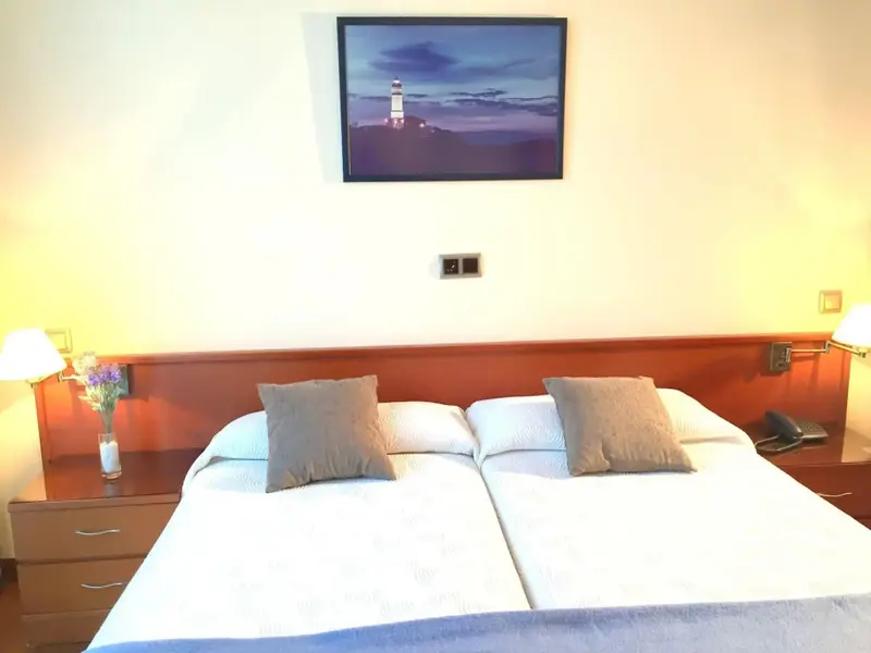 Une chambre lumineuse avec deux lits simples et une décoration sobre.