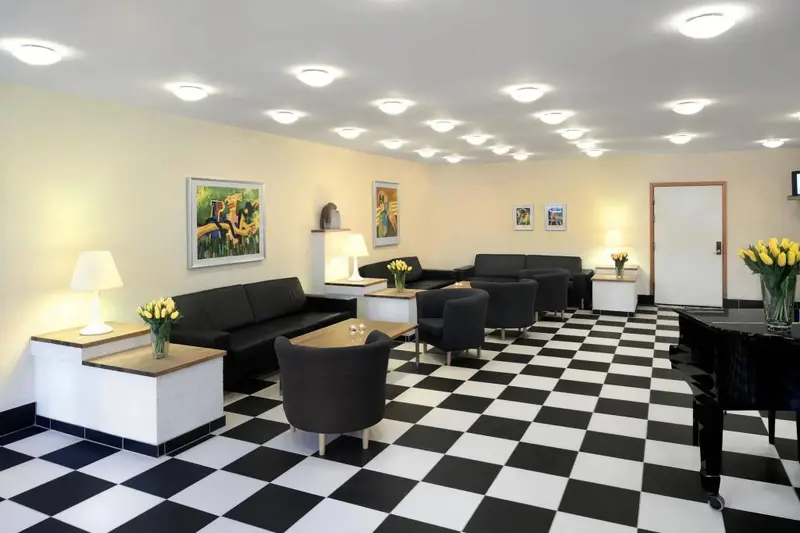 Espace de détente intérieur avec canapés, tables basses et piano à queue.
