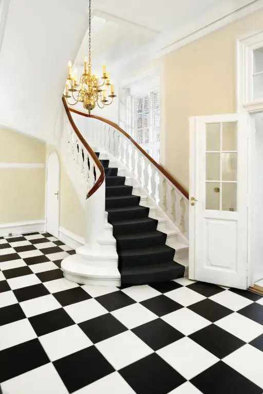 Un escalier en colimaçon noir et blanc s'élève dans un hall d'entrée lumineux.