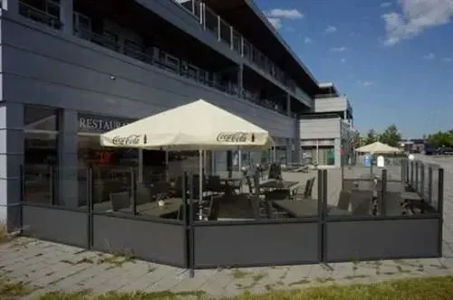 Terrasse ombragée avec tables et chaises devant un bâtiment moderne.