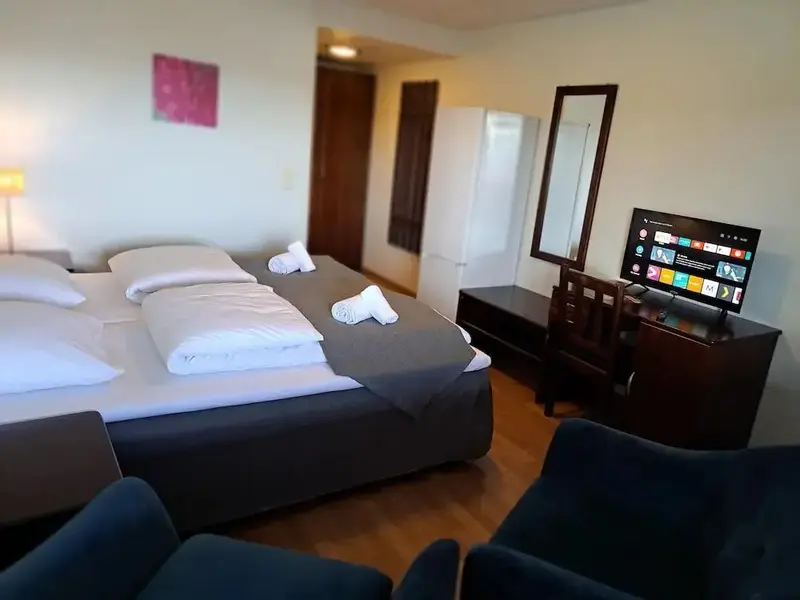 Une chambre avec un grand lit préparé et un meuble télévision.