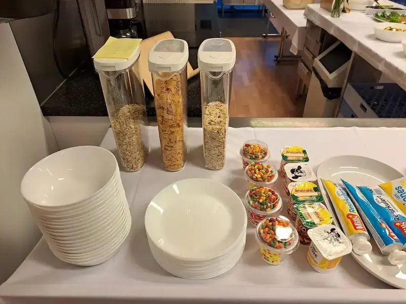 Un buffet propose des céréales, des yaourts et de la vaisselle.
