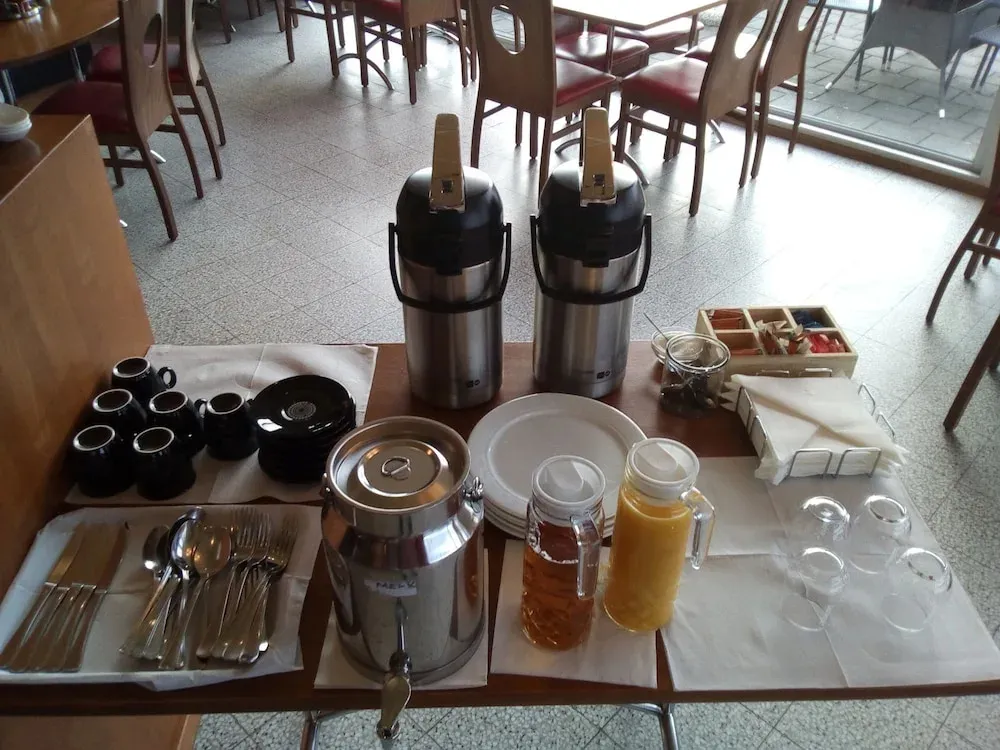 Un buffet propose des boissons chaudes, des jus de fruits et de la vaisselle.