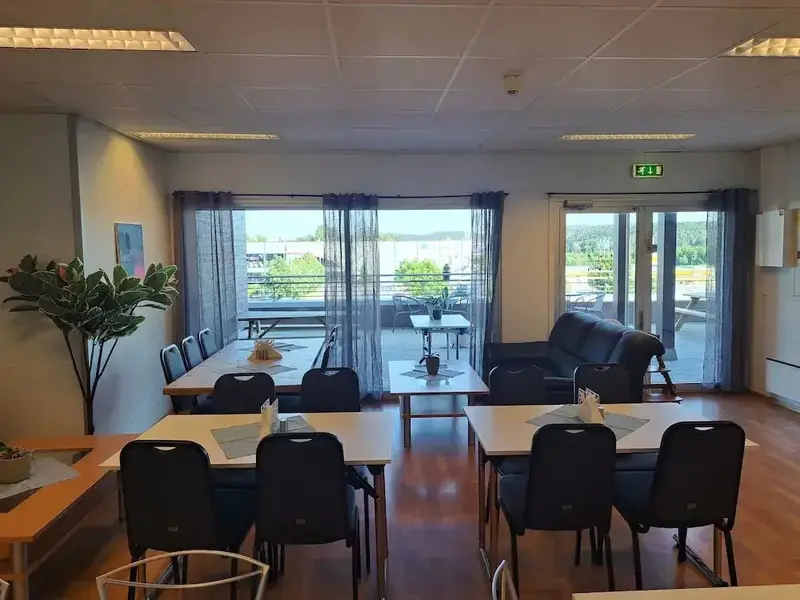 Une salle lumineuse avec des tables et des chaises, donnant sur une vue extérieure.