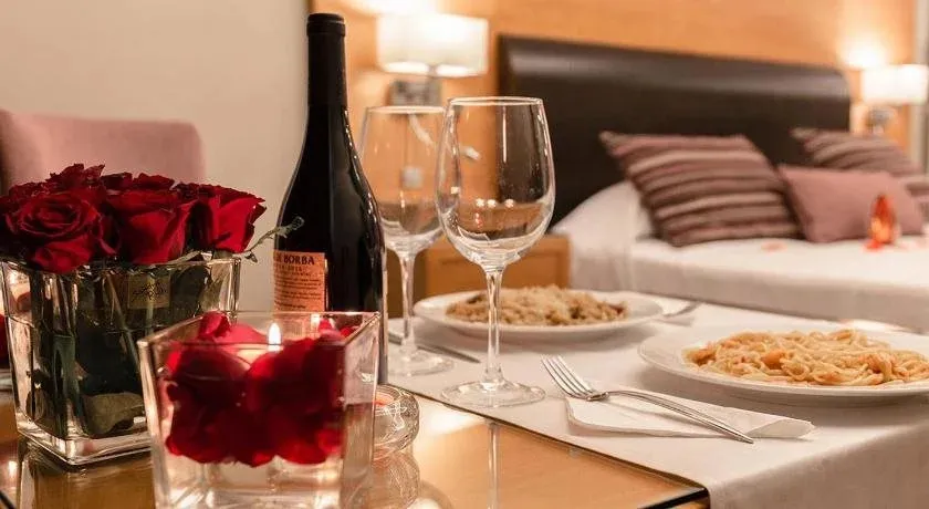 Une table est dressée avec des plats, des verres et une bouteille de vin dans une chambre d'hôtel.