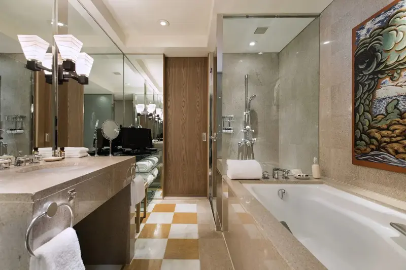 Une salle de bain lumineuse avec baignoire et grand miroir.