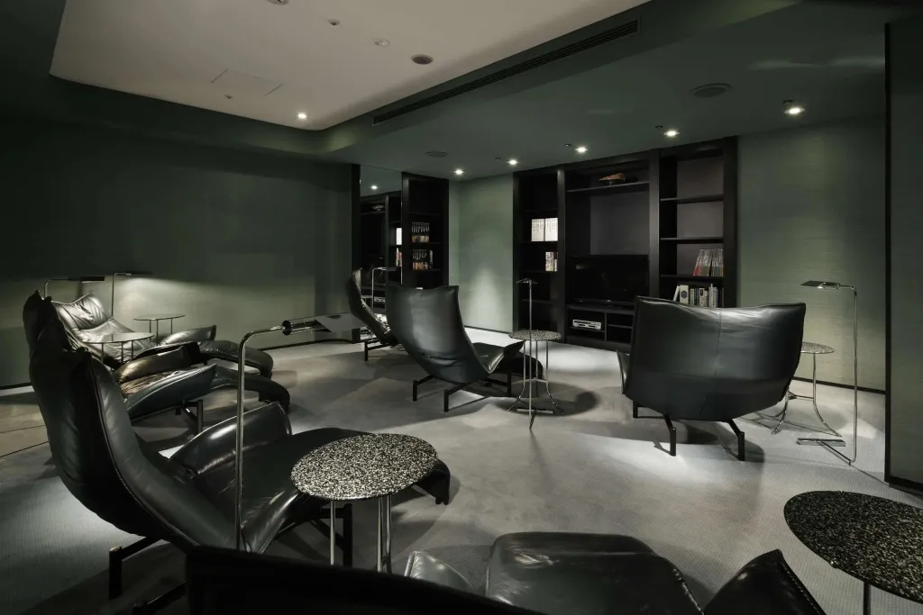 Un espace de détente intérieur avec des fauteuils et des lampes sur fond sombre.