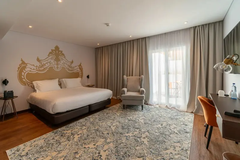 Une chambre lumineuse avec un grand lit et un fauteuil.