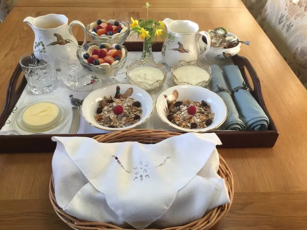 Un plateau de petit-déjeuner garni de fruits frais et de céréales est présenté sur une table en bois.