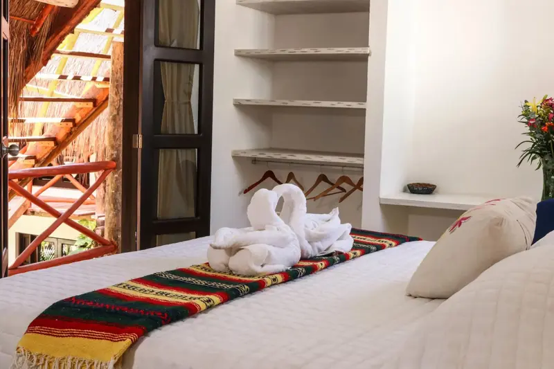 Un lit décoré de serviettes en forme de cygnes dans une chambre lumineuse.