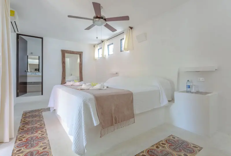 Une chambre lumineuse avec un grand lit recouvert d'une couverture beige.