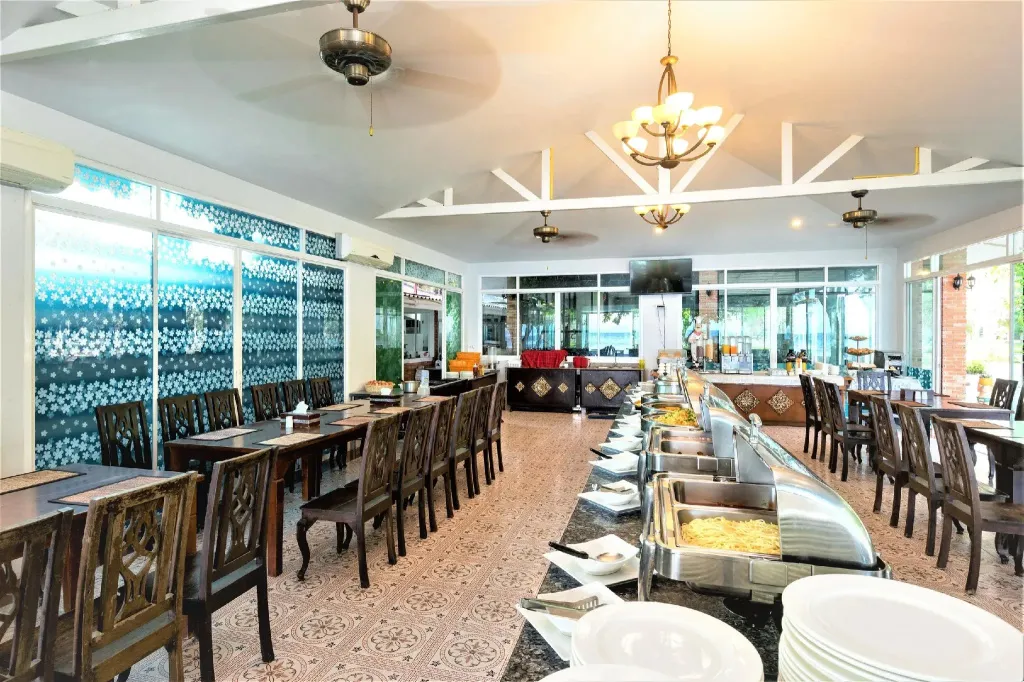 Une salle lumineuse avec des tables dressées et un buffet garni.