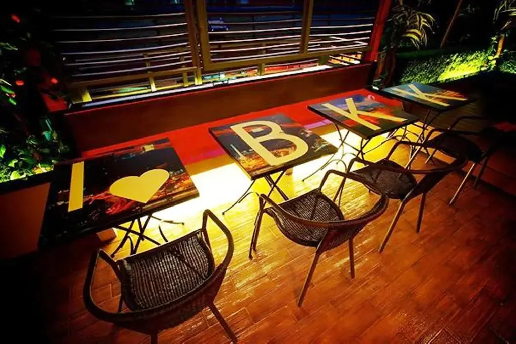 Terrasse avec tables et chaises éclairées en soirée.