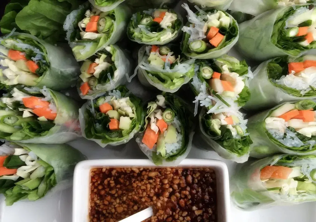 Rouleaux de printemps frais disposés sur une assiette blanche avec une sauce.
