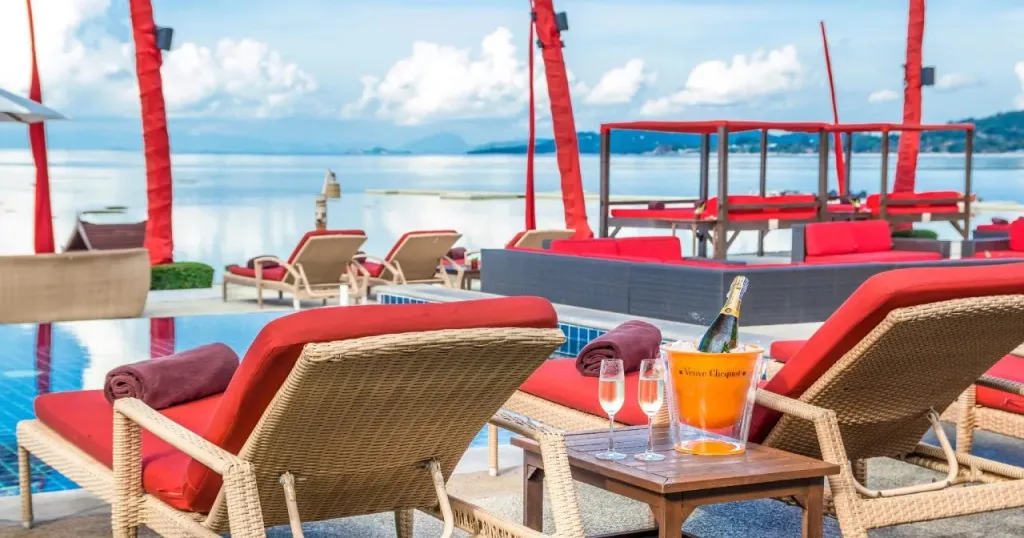 Transats et tables basses au bord d'une piscine avec vue sur la mer.