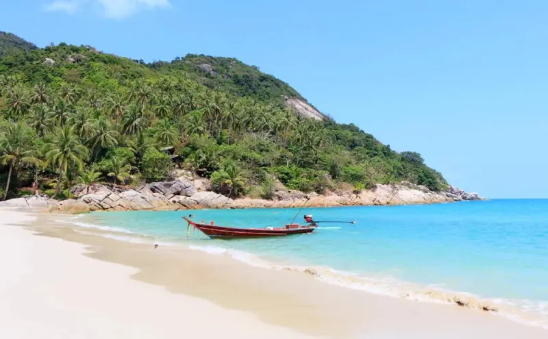 Une plage de sable fin bordée d'une eau turquoise et d'une végétation luxuriante.