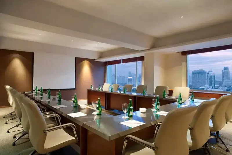 Une salle de réunion lumineuse avec une grande table et une vue sur la ville.
