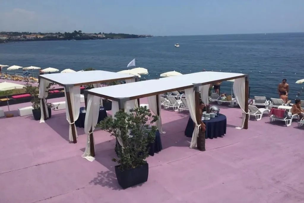 Terrasse aménagée avec des pergolas et des transats en bord de mer.