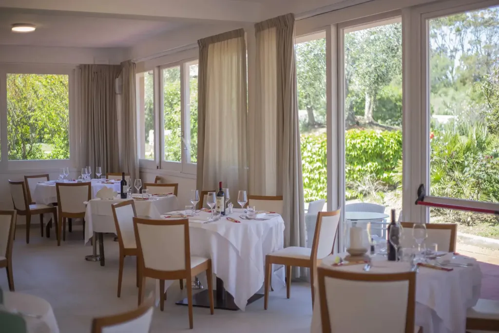 Une salle lumineuse avec des tables dressées pour un repas.