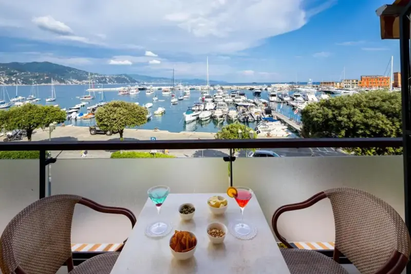 Une table avec des boissons et des amuse-gueules est mise en scène sur un balcon avec vue sur un port de plaisance.