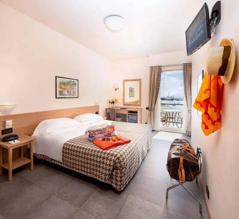 Une chambre lumineuse avec un lit recouvert d'une courtepointe et un balcon donnant sur la mer.