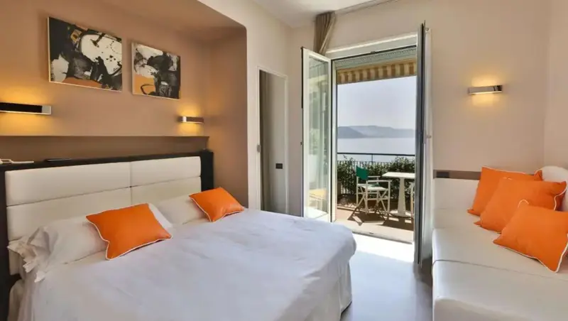 Une chambre lumineuse s'ouvre sur un balcon avec vue sur la mer.