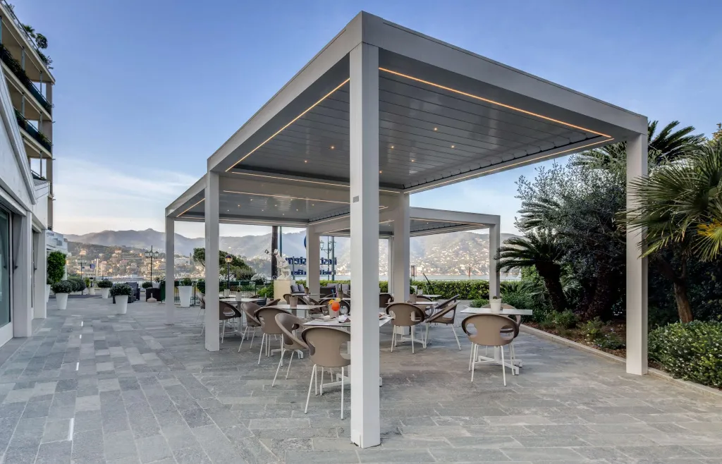 Terrasse ombragée avec tables et chaises disposées sur un sol pavé.