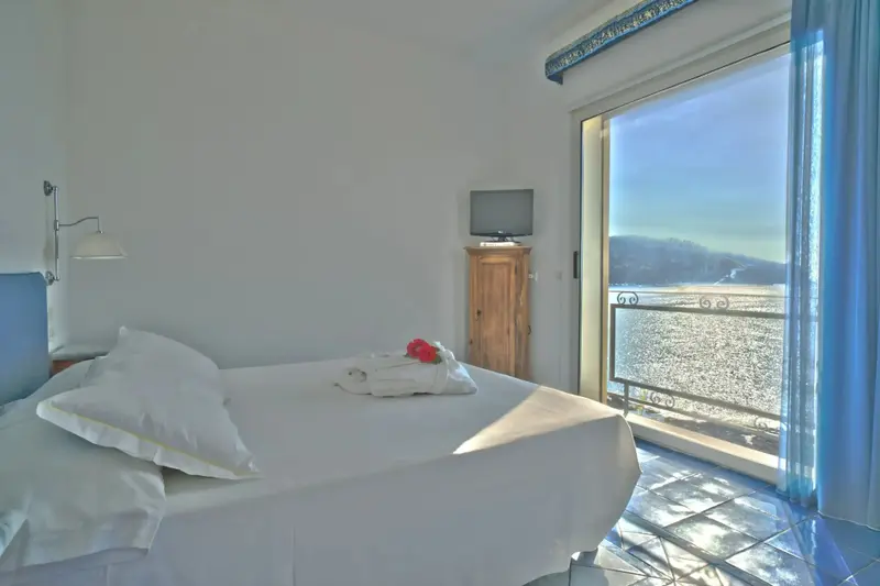 Une chambre lumineuse avec un lit blanc et une vue sur la mer.