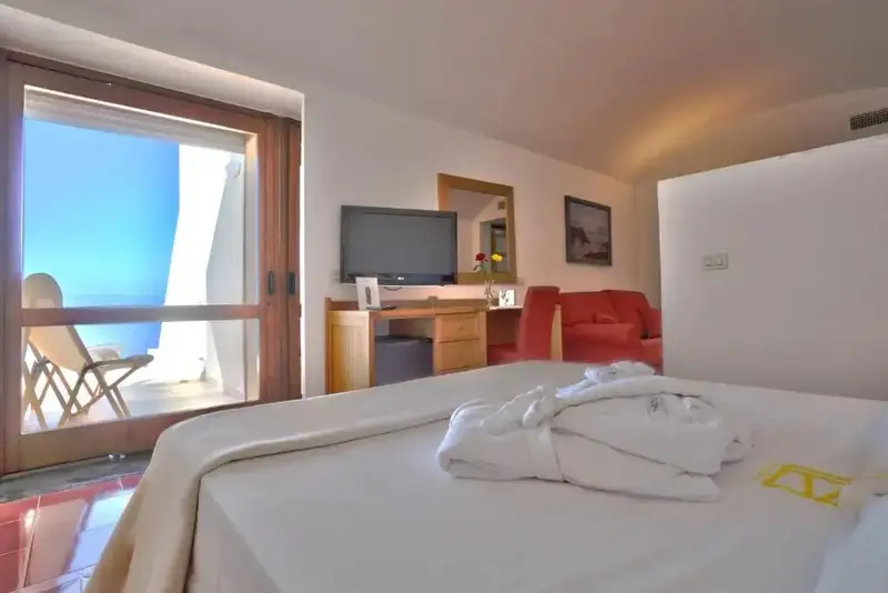 Une chambre lumineuse avec un lit fait et un accès à un balcon.