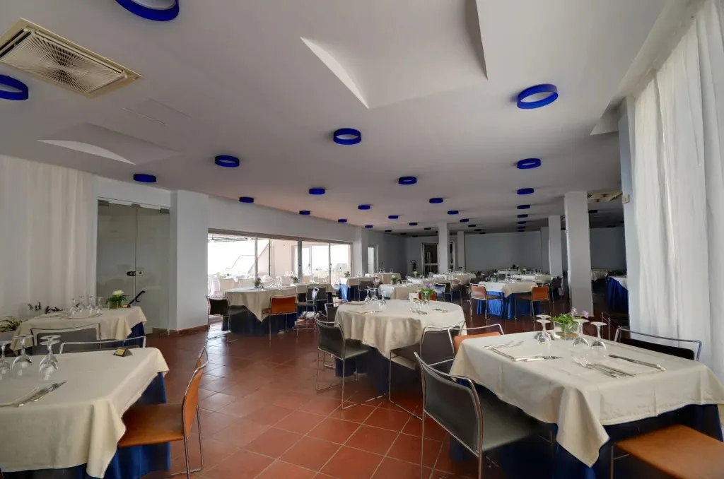 Une salle lumineuse avec des tables dressées pour un repas.
