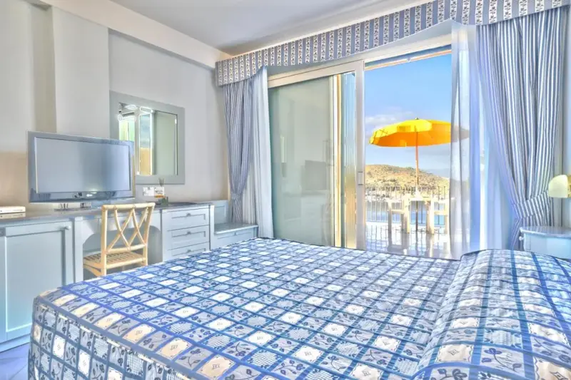 Une chambre lumineuse s'ouvre sur une terrasse avec vue sur la mer.