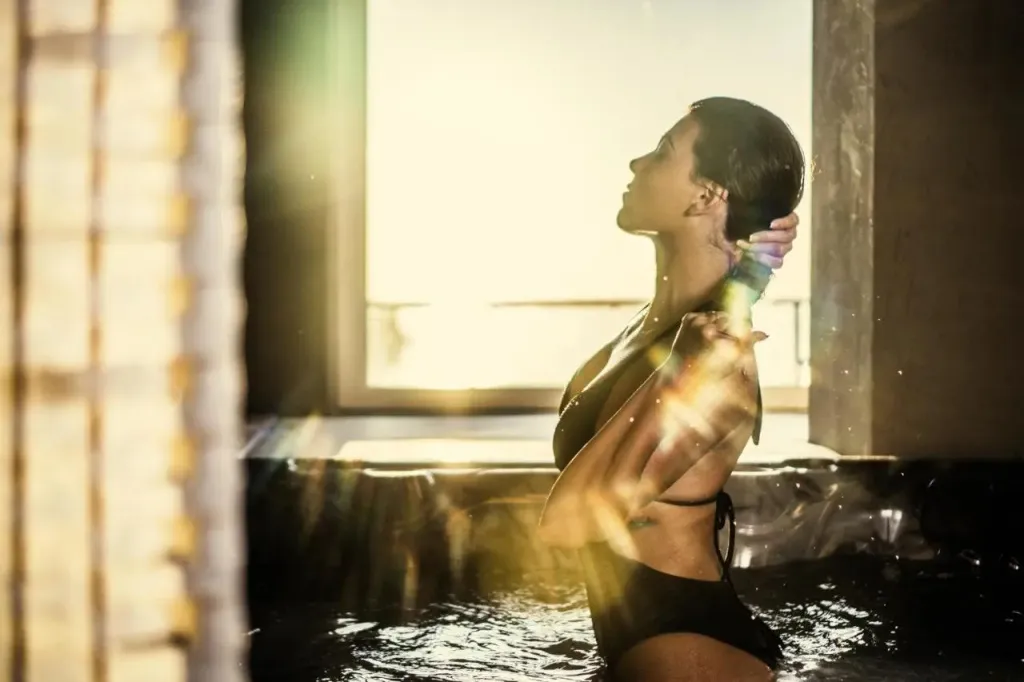 Une femme se détend dans une piscine intérieure lumineuse.