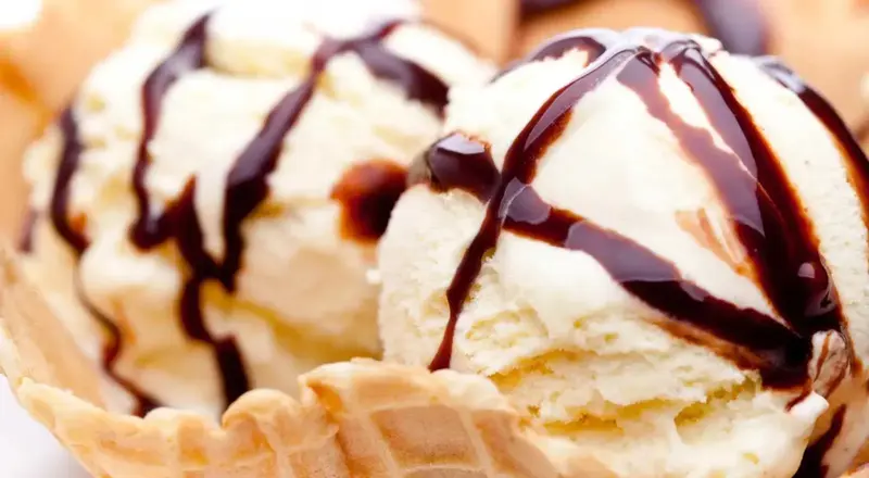 Glace à la vanille nappée de sauce chocolat servie dans un cornet.