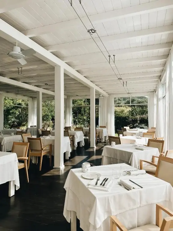 Une salle lumineuse avec des tables dressées pour le repas.