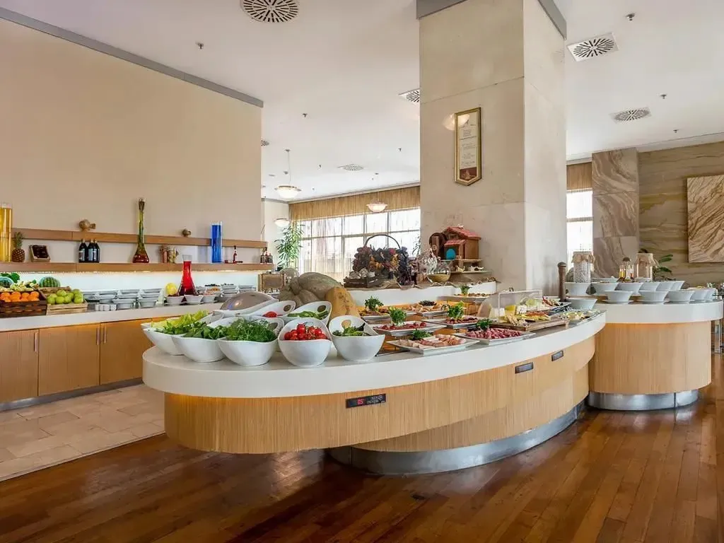 Un buffet propose une grande variété de plats frais et colorés dans une salle lumineuse.